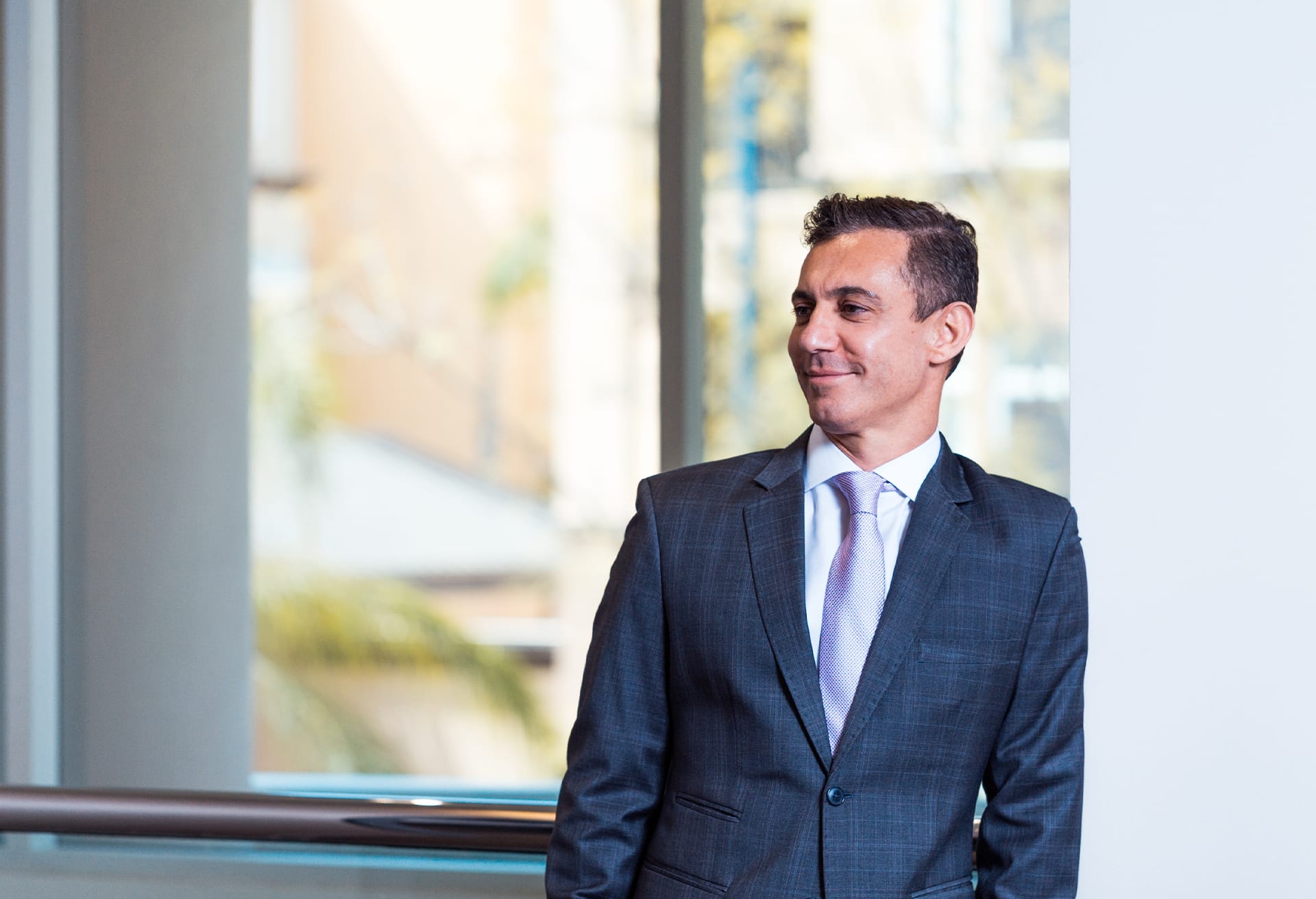 Dr. Reza Tirgari, San Diego plastic surgeon, leaning on a white column