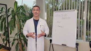 A person in a lab coat stands beside a whiteboard with notes. Green plant in background