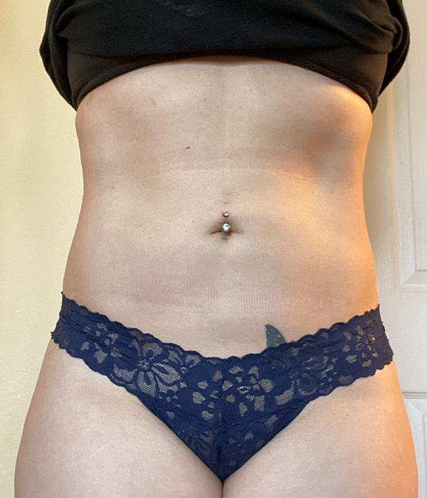 Person's midsection wearing a black shirt and navy lace underwear, with a belly button piercing
