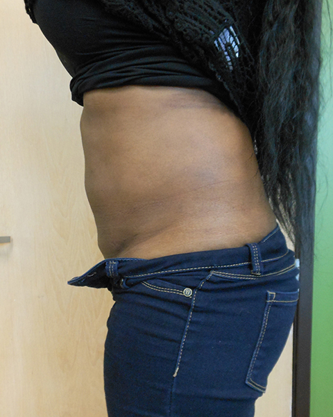 Side view of a person's midsection, wearing a black top and blue jeans, against a plain background