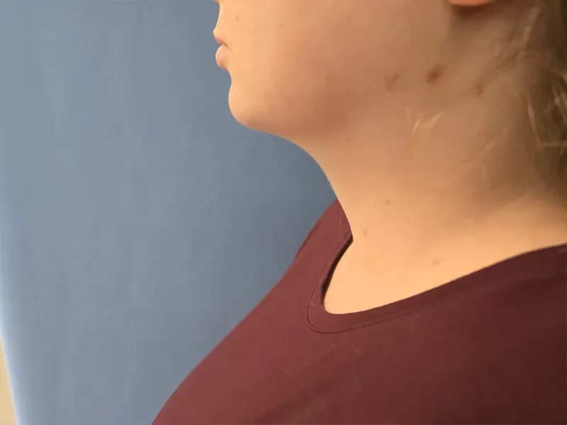 Profile view of a person with light skin, wearing a maroon shirt against a blue background