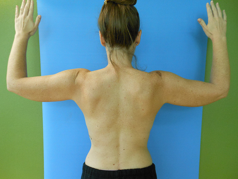 Person seen from behind with arms raised against a blue background